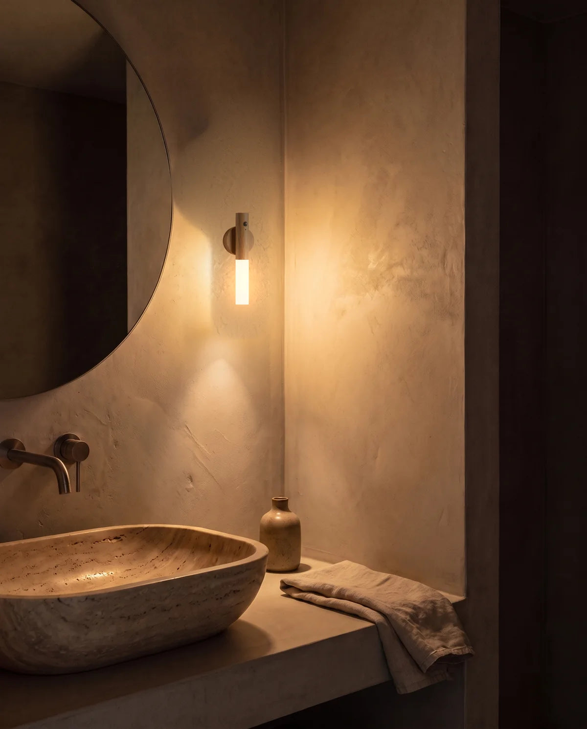 Bagno di notte illuminato da una piccola lampada SENZIA accanto allo specchio