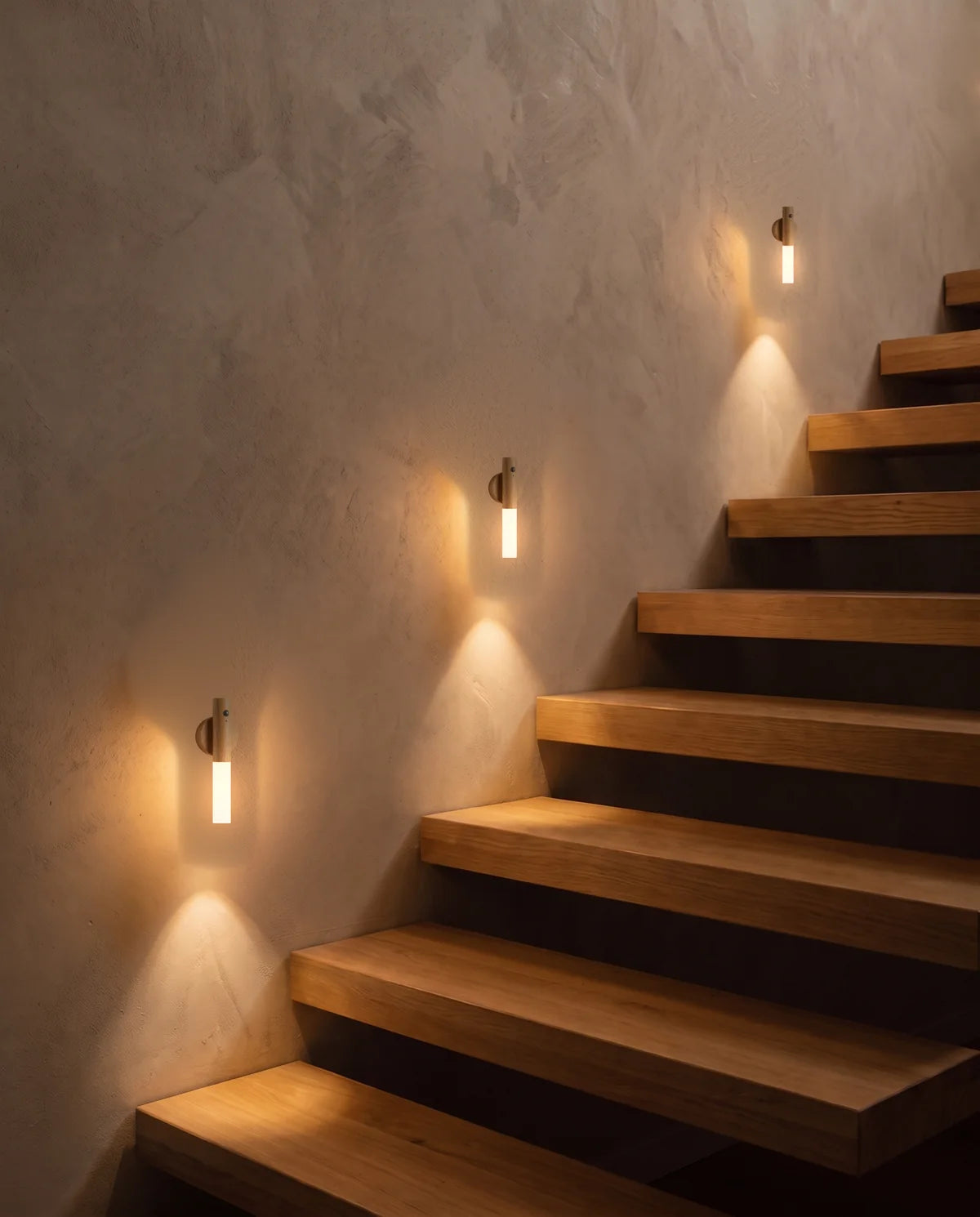Tre piccole lampade SENZIA accese lungo una scala in legno